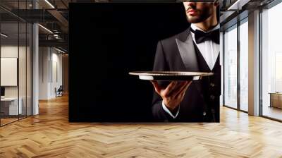 Waiter in black suit holding tray isolated on black background Wall mural