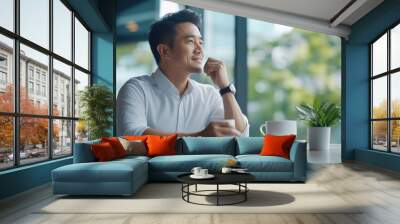 An Asian man enjoying a coffee break in a modern workspace, with a sleek and organized office setting enhancing productivity. Wall mural