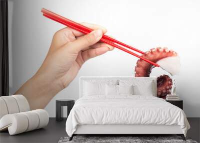 Hand holding chopsticks, eating tentacles of octopus isolated on white background Wall mural