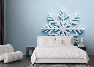 A snowflake is on a blue background. The snowflake is white and has a frosty appearance Wall mural