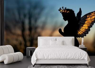 Silhouette of a Christmas angel with a halo glowing softly in the evening. Wall mural