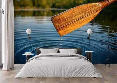 Close up of a wooden rowboat paddle dripping water on a pond lake with a shallow depth of field Wall mural