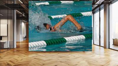 Young boy swimming a competitive freestyle swim race with green and white lane markers Wall mural