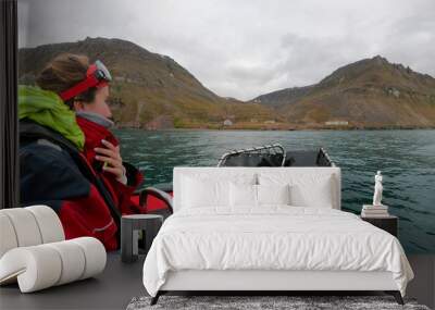 Traveler woman in an Arctic rib boat safari in Longyearbyen, Svalbard. Equiped tourist exploring Spitsbergen fjords and Arctic ocean adventure Wall mural