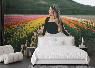 A beautiful young woman in a field of tulips in the Spring. Wall mural