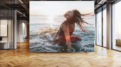 A free spirited woman in the ocean at sunset. Wall mural