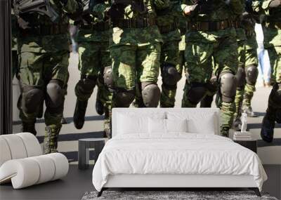 a group of male soldiers marching holding assault guns, military boots, knee protectors, green military suits Wall mural