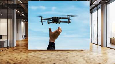 Hands reaching for drone against blue sky Wall mural