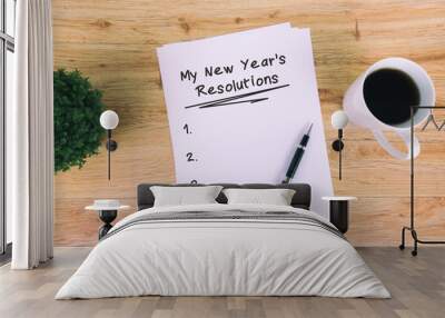 My New Year's Resolutions written on paper with cup of coffee, pen and pot of flower. Retro style wooden background. Wall mural