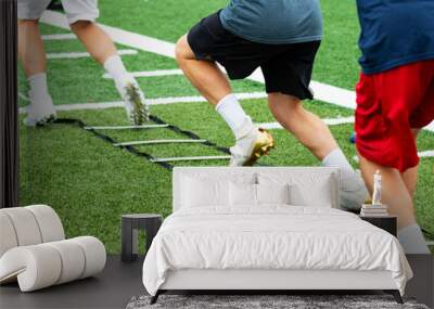 Three athletes in cleats doing ladder foot drills on turf field Wall mural