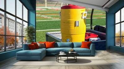 Yellow water cooler on a blue cart with soccer net in background Wall mural