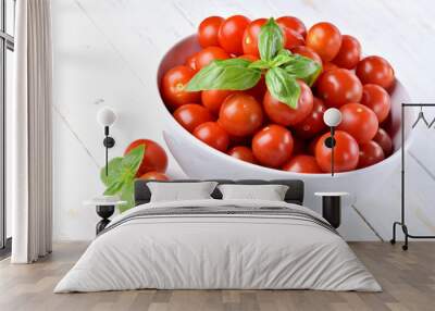 Close-up of bowl of fresh cherry tomatoes and basil leaves on rustic wooden background. Wall mural