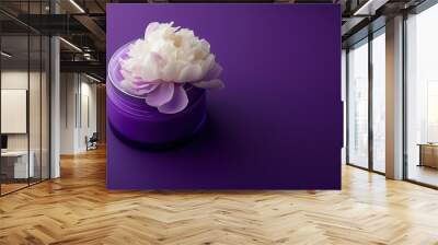 Close-up of a white peony flower resting on a purple jar. Wall mural