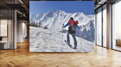 man climbing snowy mountain in  touring ski under blue sky  Wall mural