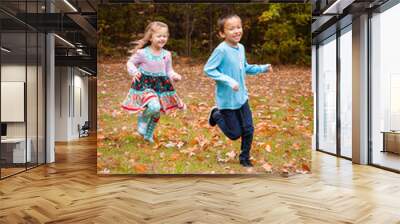 Girl chasing boy in fall Wall mural