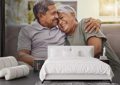 Happy, love and senior couple on a sofa hugging, bonding and relaxing together in their living room. Happiness, laugh and elderly man and woman pensioners in retirement embracing on a couch at home. Wall mural