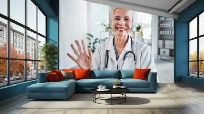 Video call, smile and wave, portrait of woman doctor in hospital office, communication and success in medical work. Health, medicine and face of confident mature professional and online consultation. Wall mural