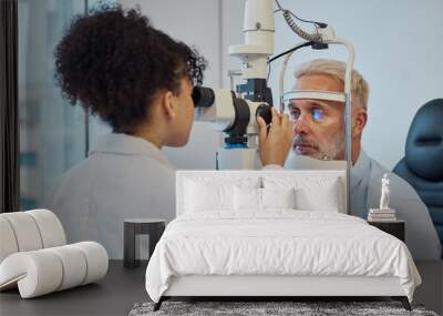 Vision, eye exam and healthcare with a doctor woman or optometrist testing the eyes of a man patient in a clinic. Hospital, medical or consulting with a female eyesight specialist and senior male Wall mural