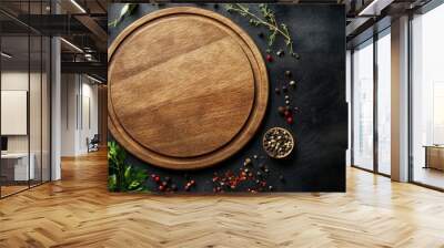 Empty wooden round board on a dark background with herbs and spices scattered around it, top view. Banner for menu design in photo stock style Wall mural