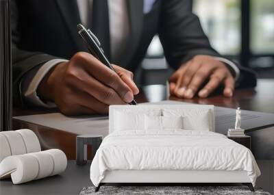 Close-up of a businessperson in a suit signing a document at a desk. The professional environment and the focused action reflect responsibility and attention to detail.  Wall mural