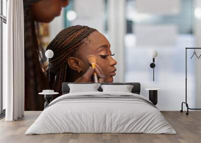 A black make up artist applying blush to a black model with pigtails. Wall mural