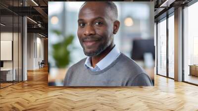 Close-up of a smiling, confident black man wearing a shirt and grey jumper and looking into the camera. Wall mural