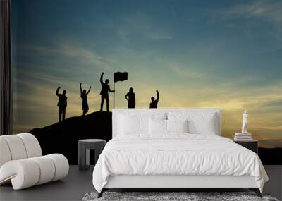 Silhouette of people are celebrating success at the top of the mountain, sky and sun light background. Team business concept. Wall mural