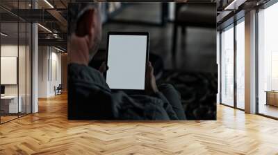 Application mockupover the shoulder shot of a man holding an ebook with a completely black screen Wall mural