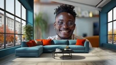 Portrait of a grinning afro-american man in his 20s smiling at the camera in modern minimalist interior Wall mural