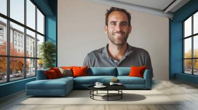 Portrait of a happy caucasian man in his 30s donning a classy polo shirt over minimalist or empty room background Wall mural