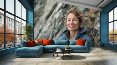 Portrait of a joyful woman in her 40s wearing a zip-up fleece hoodie in rocky cliff background Wall mural