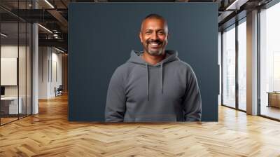 Portrait of a smiling indian man in his 40s sporting a comfortable hoodie over minimalist or empty room background Wall mural