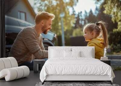 A white father teaches his daughter to charge an electric car, both smiling outside by a black car, bonding joyfully in the activity. Wall mural