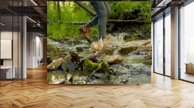 Female hiker splashing through a forest stream Wall mural