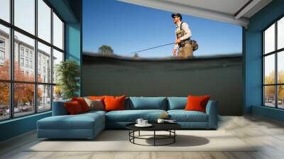 Over underwater shot of a man fly fishing in the summer in a river Wall mural