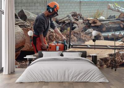 Lumberjack cutting tree trunk with giant chainsaw to make wooden planks Wall mural