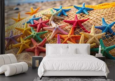 A fishing net filled with colorful starfish on a sandy beach Wall mural