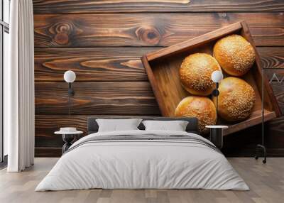 Homemade sesame buns for burgers in a wooden box on a brown wooden table, top view close up Wall mural