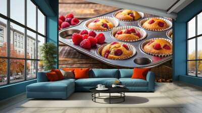 Two baking tins filled with freshly baked raspberry muffins or cupcakes on a rustic kitchen counter Wall mural