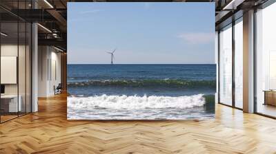 A wind turbine out on the ocean with gentle waves in front Wall mural