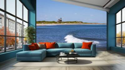 lighthouse on a beach with blue water and a wave Wall mural