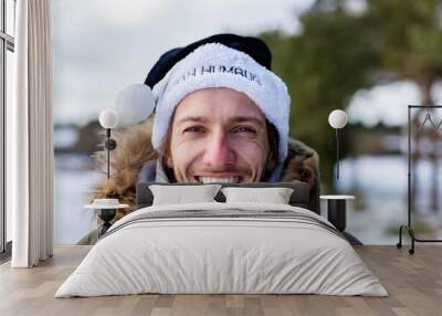 A ironic portrait of a smiling and happy young man wearing a black santa hat with the words Bah Humbug written on it Wall mural