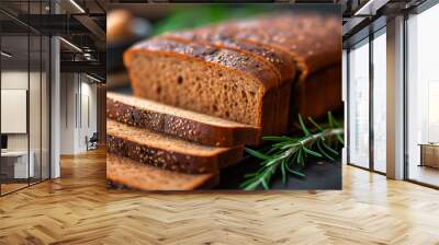 Freshly baked whole grain bread loaf with rosemary on dark surface. Concept of artisanal baking and healthy nutrition. Wall mural