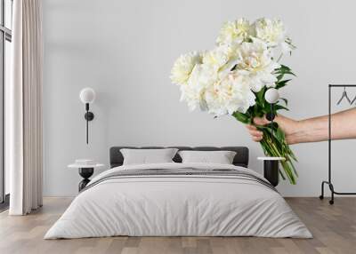 Male hand holds beautiful bouquet of white peonies. Flower delivery concept Wall mural