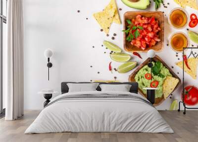 Mexican food selection: sauce guacamole, salsa, chips and tequila shots with lime on white background Wall mural