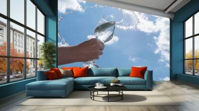 Concept. Wine glass against the blue sky. Beautiful splashes from the glass. Wall mural