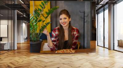 Beautiful and sexy girl sitting at a table with a pizza in a cafe. Wall mural