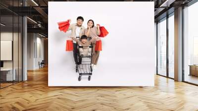 Asian little boy sitting inside of shopping trolley and holding shopping bag and Father and mother pushing shopping cart isolated on white background, Family and shopping mall concept Wall mural