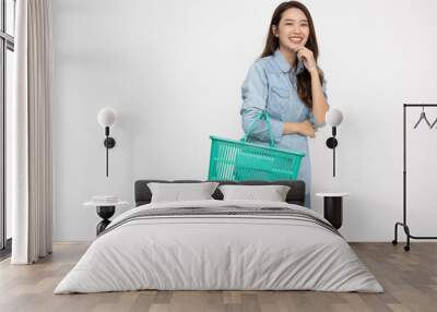 Asian woman in jeans shirt smiling and holding grocery basket isolated on white background, Shopping and Supermarket concept Wall mural