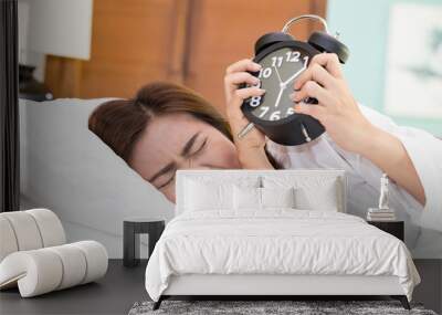 Asian woman lying in bed suffering from alarm clock sound. Not e Wall mural